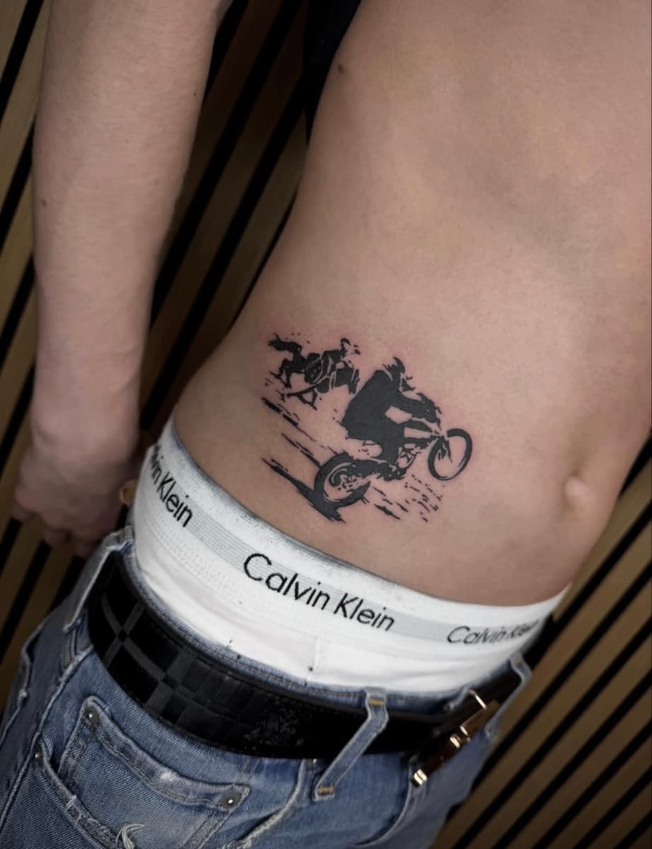 Fine line script tattoo reading “Made in heaven” on the side of the ribs