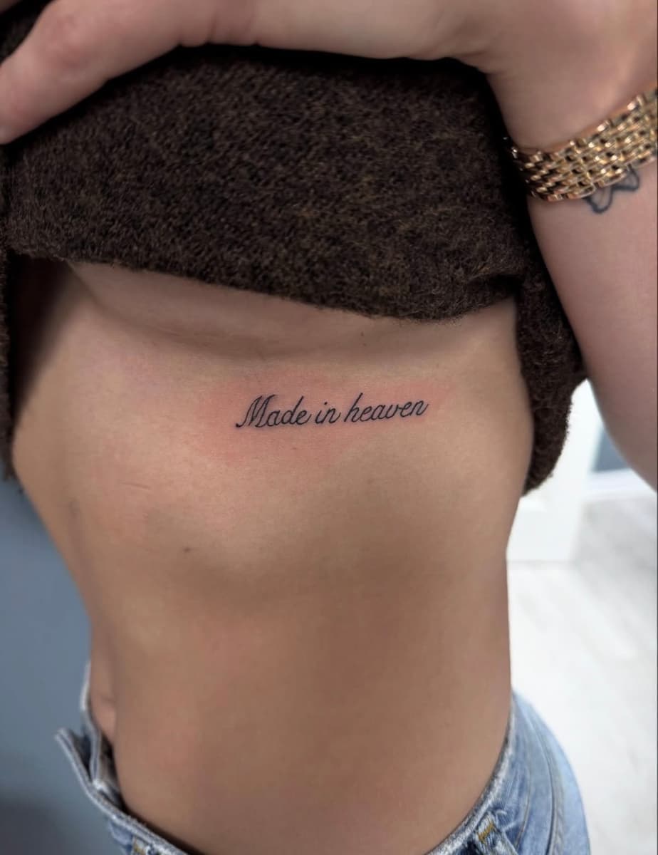 Solid black silhouette tattoo of a motocross rider doing a wheelie on the lower side torso