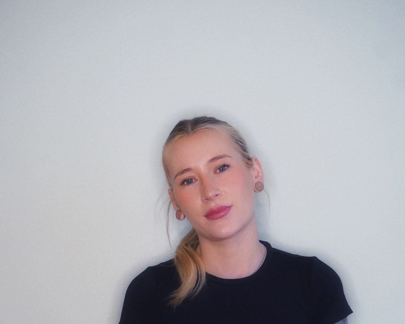 Woman with blonde hair standing against a wall