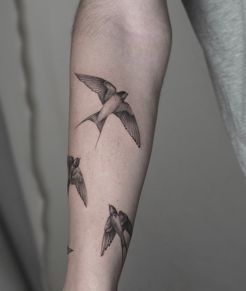 Minimal black and grey botanical tattoo with wildflowers and leaves on the forearm