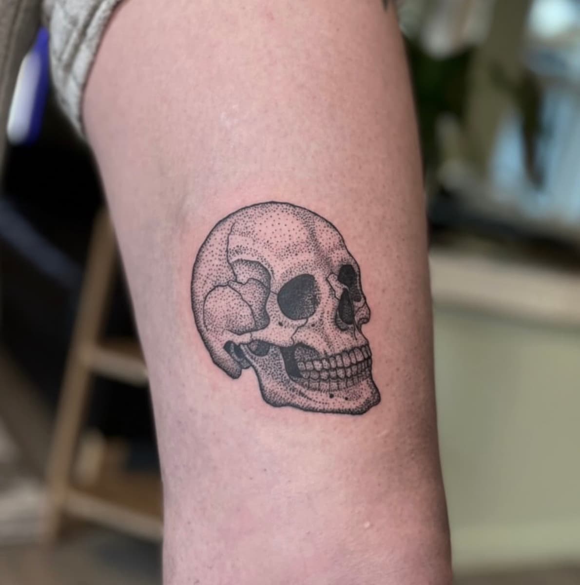 Black and grey butterfly tattoo flash design on white paper held in front of green houseplants